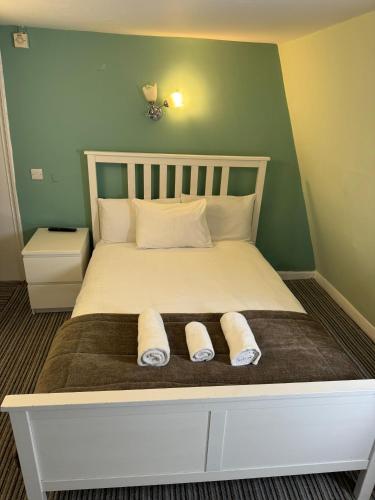 a bedroom with a bed with two slippers on it at The George Hotel in Battle
