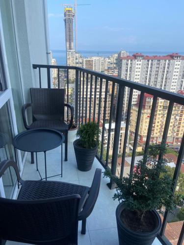 a balcony with two chairs and a table and plants at Панорама-Батуми in Batumi