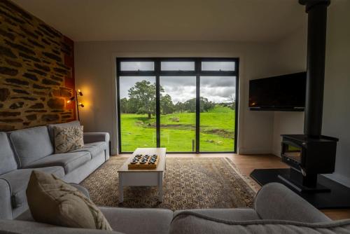 a living room with a couch and a tv and a window at The Old Farm Cottage, Mount Torrens in Mount Torrens