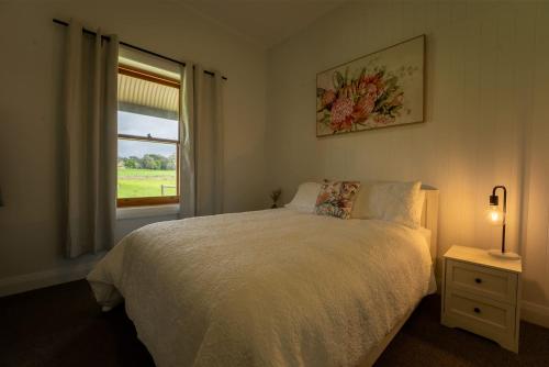 a bedroom with a white bed and a window at The Old Farm Cottage, Mount Torrens in Mount Torrens