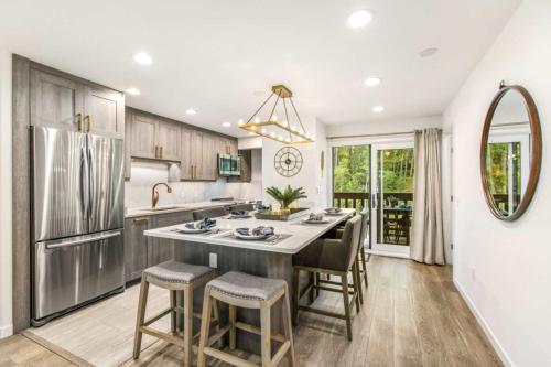 a kitchen with a large island with bar stools at Designer 2 BR on River with Pool - Walk to Town! in Aspen