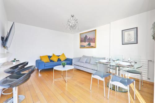 un salon avec un canapé bleu, une table et des chaises dans l'établissement Appartement Quartier Tour Eiffel 6 Free Netflix, à Paris