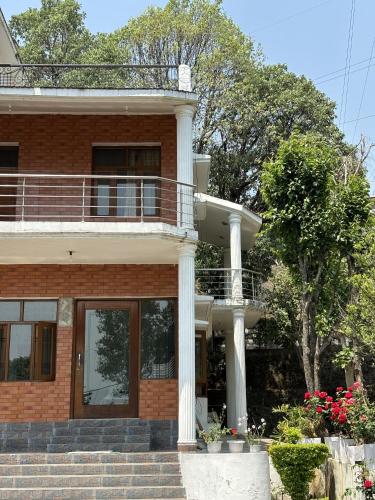 a brick house with a balcony and stairs at Chirping Hills Resort,Bhimtal in Bhīm Tāl