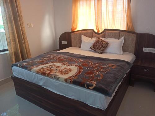 a bedroom with a large bed with a blanket on it at Abhiram Homestay in Khajurāho