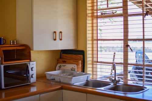 une cuisine avec un évier et un micro-ondes dans l'établissement Dabchick Cottage, à Dullstroom