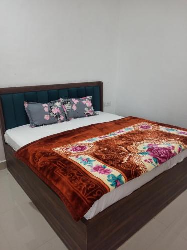 a bed with a blanket and pillows on it at Abhiram Homestay in Khajurāho