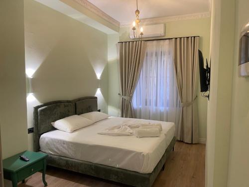 a bedroom with a bed with white sheets and a window at Amorino Tirana B&B in Tirana