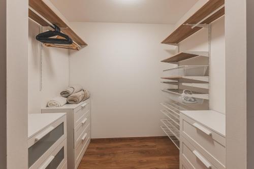 a walk in closet with white cabinets and shelves at Luxusní Apartmán U Petrofa s vlastním parkovacím místem in Hradec Králové