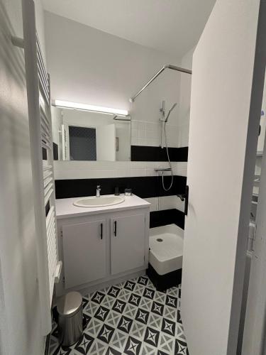 une salle de bain blanche avec un lavabo et des toilettes dans l'établissement Le Lagon - Studio - 1 chambre - 2 personnes, à Châtel-Guyon