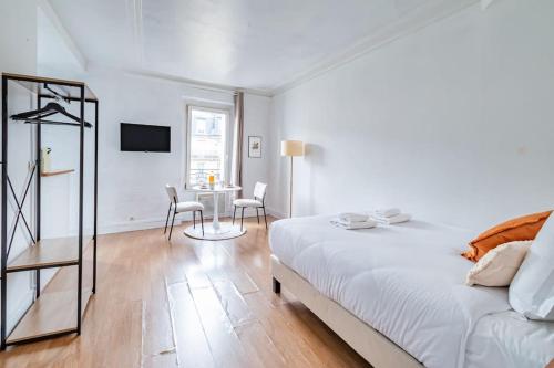 une chambre blanche avec un lit et une table dans l'établissement Charmant Studio Proche Nation, Paris - II, à Paris