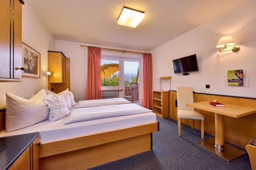 a hotel room with a large bed and a desk at AURA-HOTEL Saulgrub in Saulgrub