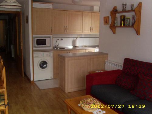a living room with a red couch and a kitchen at FORMIGAL Edificio PORTALET II in Formigal