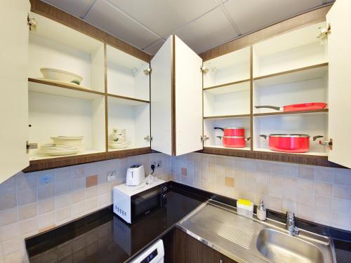 a kitchen with white cabinets and a sink at HARF2401 Chic Studio in Al Reem in Abu Dhabi
