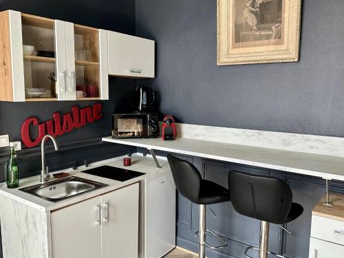 une cuisine avec un évier et un comptoir avec des chaises dans l'établissement L'élégant - Gare Centre - 2 Pers, au Mans