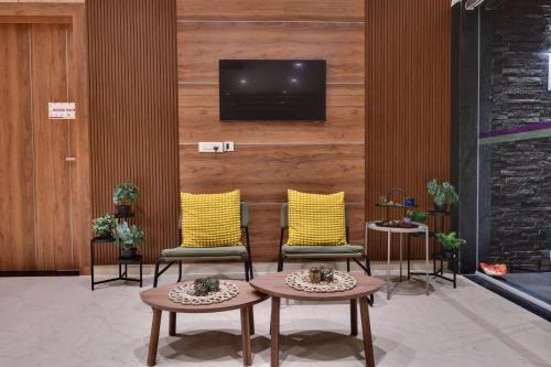 a lobby with two chairs and a tv on a wall at Click Hotel Vista-Kempegowda Airport in Bengaluru