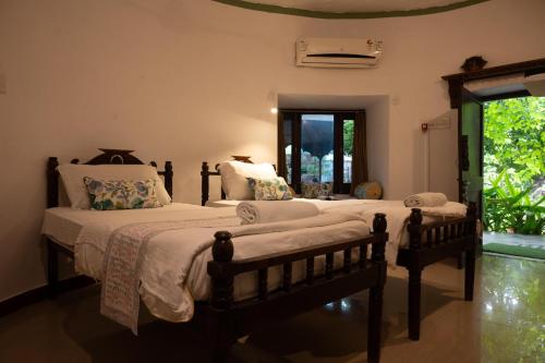 a bedroom with two beds and a large window at The Mandore - a leafy resort in Jodhpur