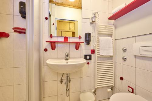a bathroom with a sink and a toilet and a mirror at AURA-HOTEL Saulgrub in Oberammergau