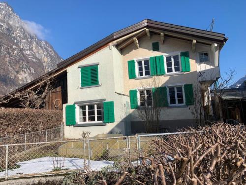 a house with green shuttered windows and a mountain at Revier Grosi's Art in Netstal