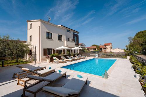 a villa with a swimming pool and a house at Mediterranes Apartment nur 100 Meter zum Strand mit Salzwasserpool und Jacuzzi in Funtana