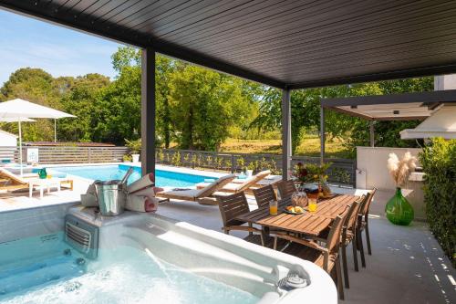 a swimming pool with a hot tub and a table and chairs at Mediterranes Apartment nur 100 Meter zum Strand mit Salzwasserpool und Jacuzzi in Funtana