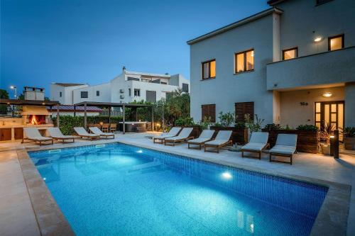 a swimming pool with lounge chairs next to a house at Mediterranes Apartment nur 100 Meter zum Strand mit Salzwasserpool und Jacuzzi in Funtana