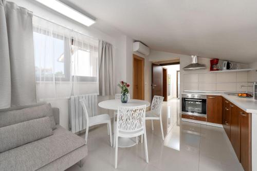 a kitchen with a table and chairs in a room at Traumhaftes Apartment nur 100 Meter zum Strand mit Jacuzzi, Meerblick, Salzwasserpool in Funtana