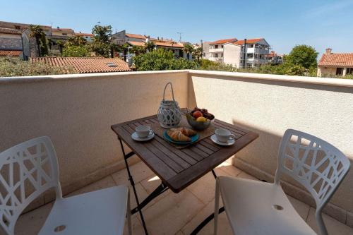 a small table with a bowl of fruit on a balcony at Extravagantes Apartment nur 100 Meter zum Strand mit Salzwasserpool und Jacuzzi in Funtana