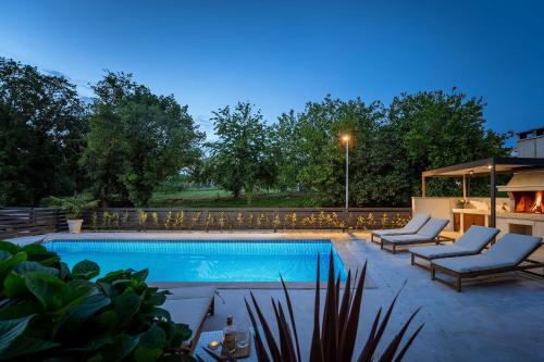 a swimming pool with two lounge chairs next to at Extravagantes Apartment nur 100 Meter zum Strand mit Salzwasserpool und Jacuzzi in Funtana