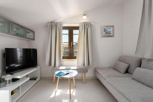 a living room with a couch and a tv at Traumhaftes Apartment nur 100 Meter zum Strand mit Jacuzzi, Meerblick, Salzwasserpool in Funtana