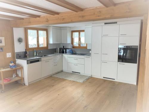a kitchen with white cabinets and a wooden floor at Revier Sytli im Höcheli in Braunwald