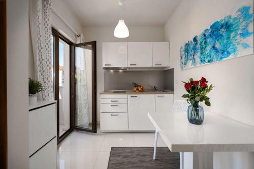 a white kitchen with a vase of flowers on a table at Extravagantes Apartment nur 100 Meter zum Strand mit Salzwasserpool und Jacuzzi in Funtana