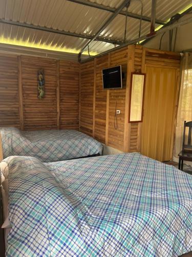 a bedroom with two beds and a tv on the wall at Cabañas venado in Venado