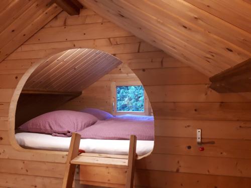 a bed in a log cabin with a window at Familienfreundliches Ferienhaus am Grinderwald nah Steinhuder Meer in Neustadt am Rübenberge