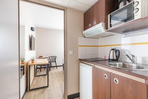 a kitchen with a sink and a table at Appart'City Classic Montelimar in Montélimar