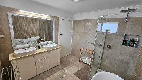 WaikerieにあるSpacious Holiday Home - Waikerieの洗面台2つとシャワー付きのバスルーム