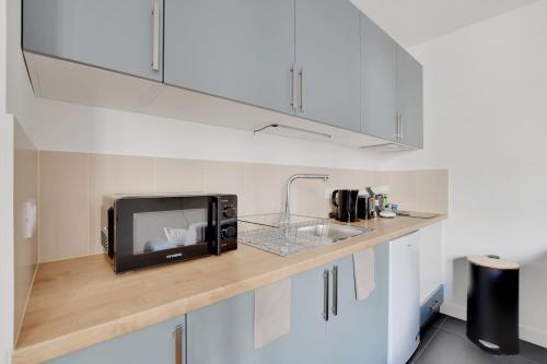 une cuisine avec un micro-ondes et un évier dans l'établissement Flexliving - Studio - Fessart, à Paris