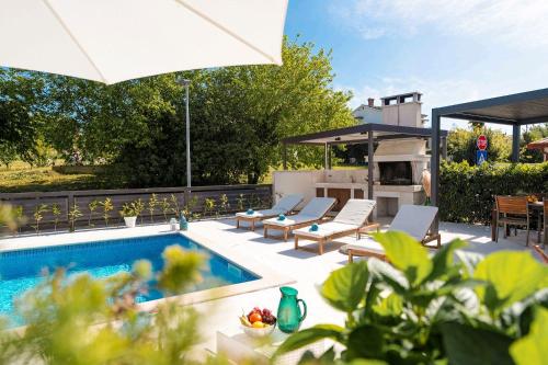 a swimming pool with lounge chairs and an umbrella at Traumhaftes Apartment nur 100 Meter zum Strand mit Jacuzzi, Meerblick, Salzwasserpool in Funtana