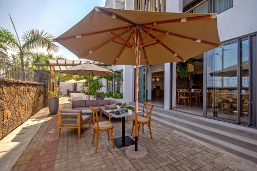 a table and chairs with an umbrella on a patio at Gosun Beach Hotel in Flic-en-Flac
