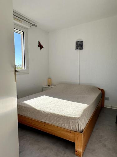 une chambre avec un lit dans une pièce avec une fenêtre dans l'établissement Appartement cosy en bord de mer, à La Londe-les-Maures