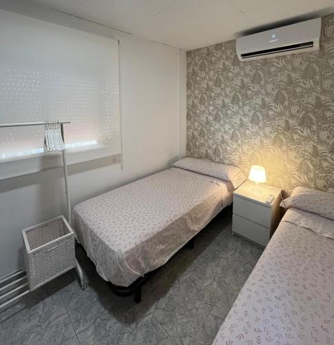 a small bedroom with two beds and a window at Casa Pagan in Cullera