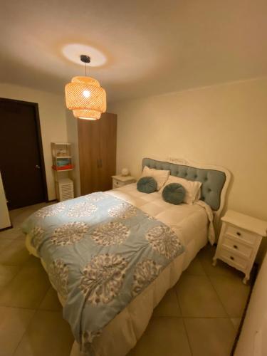 a bedroom with a bed and a chandelier at Acogedor departamento en condominio in Talca