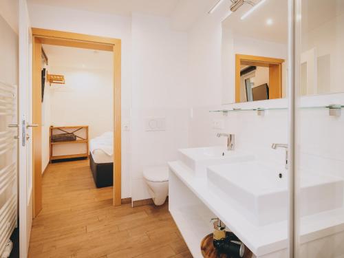 a white bathroom with a sink and a toilet at Appartements Prielau by we rent, SUMMERCARD INCLUDED in Zell am See