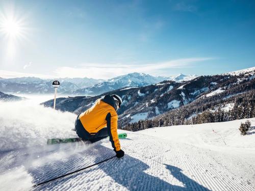 a man riding a snowboard down a snow covered slope at Appartements Prielau by we rent, SUMMERCARD INCLUDED in Zell am See