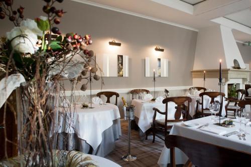 a restaurant with white tables and chairs and flowers at Schloss Hotel Dresden Pillnitz in Dresden