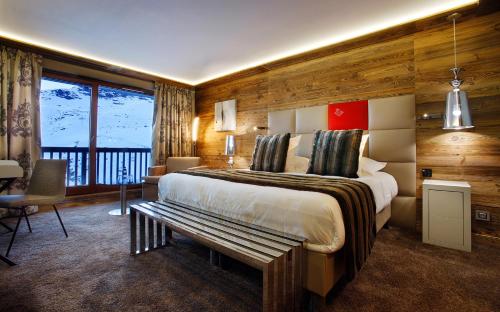 a bedroom with a large bed with a bench in it at Hôtel Koh-I Nor by Les Etincelles in Val Thorens