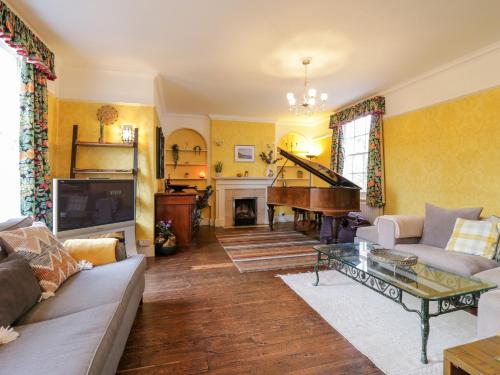 a living room with a couch and a piano at Rough Hill House in Chelmsford