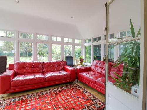a living room with two red leather couches at Rough Hill House in Chelmsford