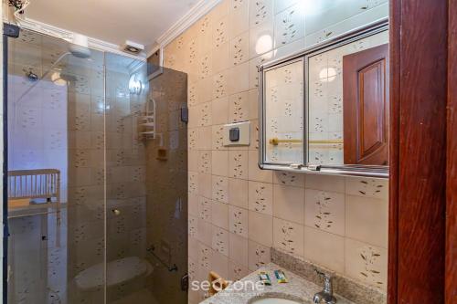 ein Badezimmer mit Glasdusche und Waschbecken in der Unterkunft Apto Aconchegante a 350m da Praia do Forte ECF0306 in Škorak