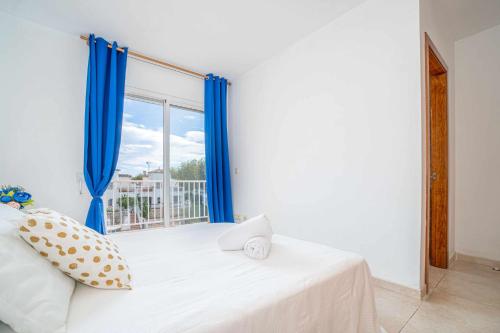 a bedroom with a bed with blue curtains and a window at Jouvacations Villa Freser 1 con piscina comunitari in Empuriabrava