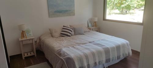 a bedroom with a bed with pillows and a window at Manantial MAR AZUL in Mar Azul